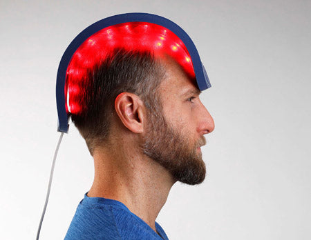Man using a hair restoration LED light therapy device