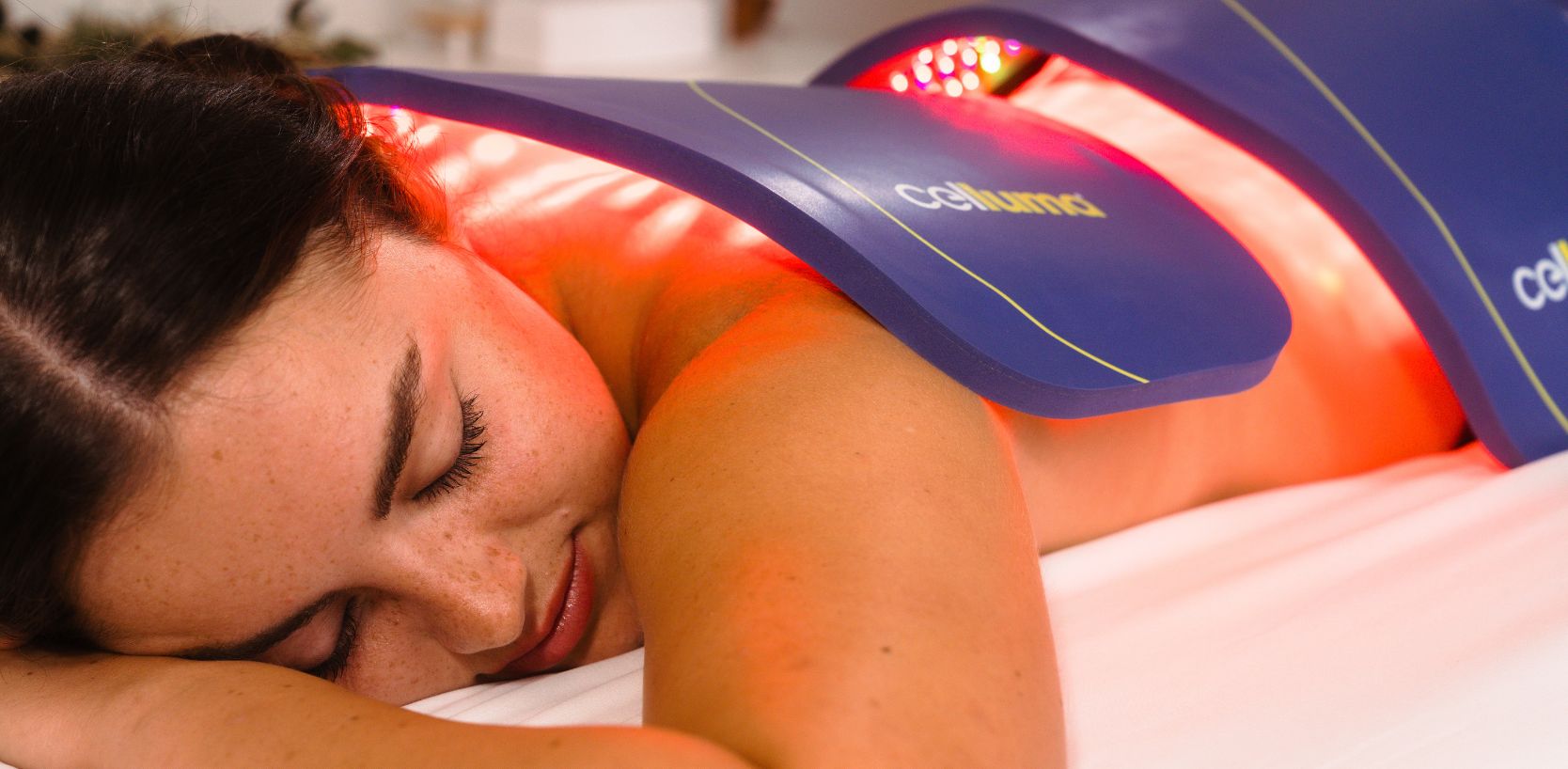 Woman receiving pain treatment and cellular rejuvenation with red light therapy LED panels made by Celluma.