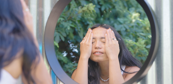 Woman looking in the mirror after washing her face and beginning her wellness routine