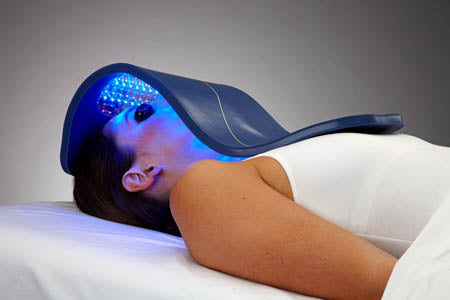 Woman laying down and using a Celluma light therapy product
